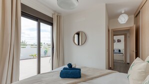 Et hotelværelse med en seng, et rundt spejl og udsigt udad.