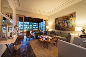 Un amplio salón con un gran ventanal, un sofá cómodo, una mesa de centro y una lámpara decorativa.