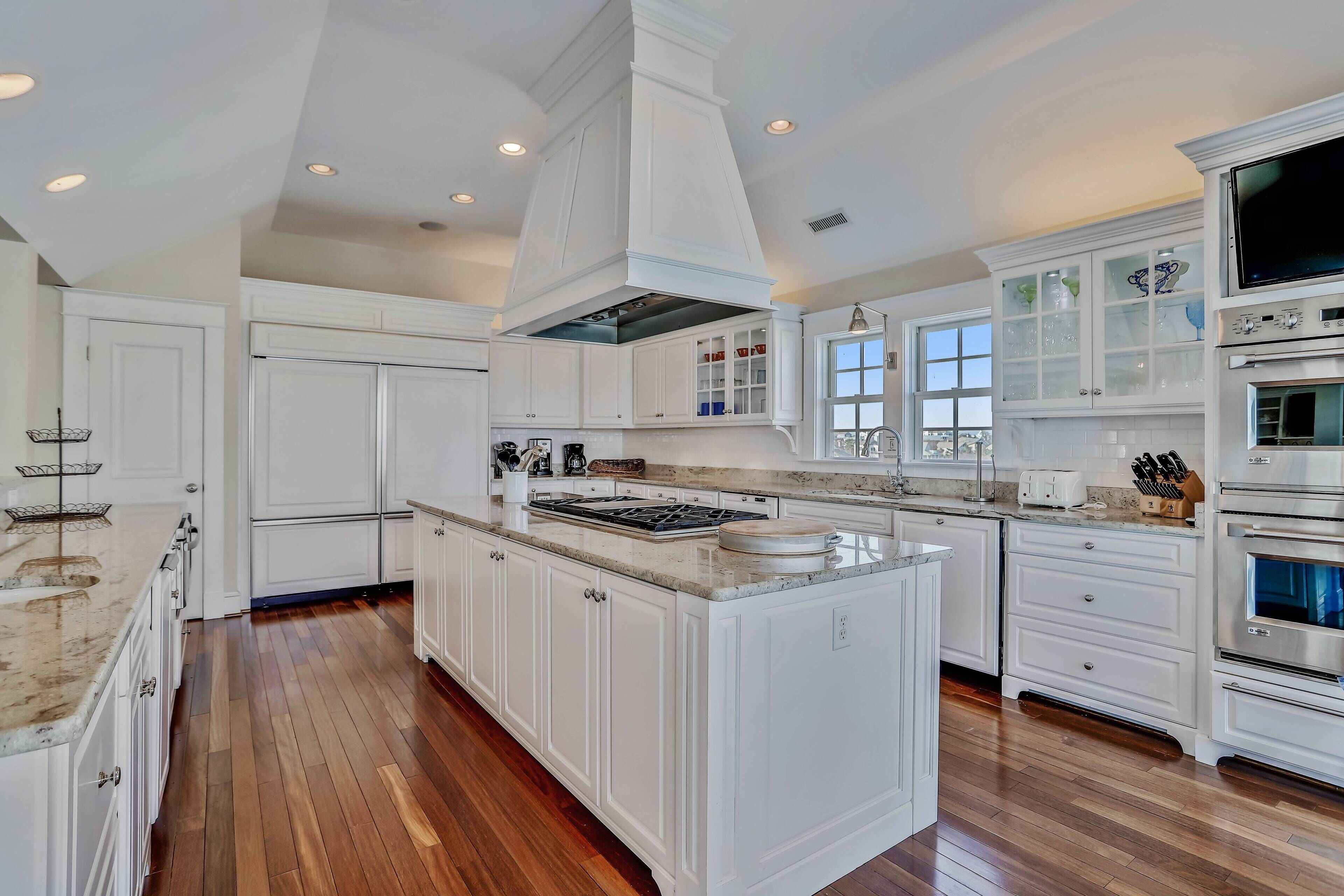 A spacious kitchen with white cabinetry, a large island, and built-in appliances.