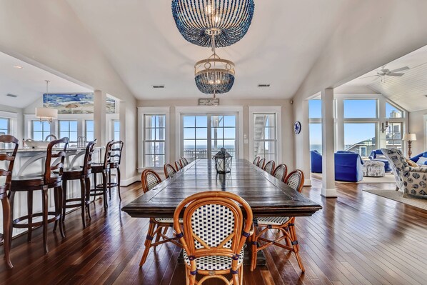Enjoy meals in this elegant dining area with a long table, high ceiling, and comfortable seating.