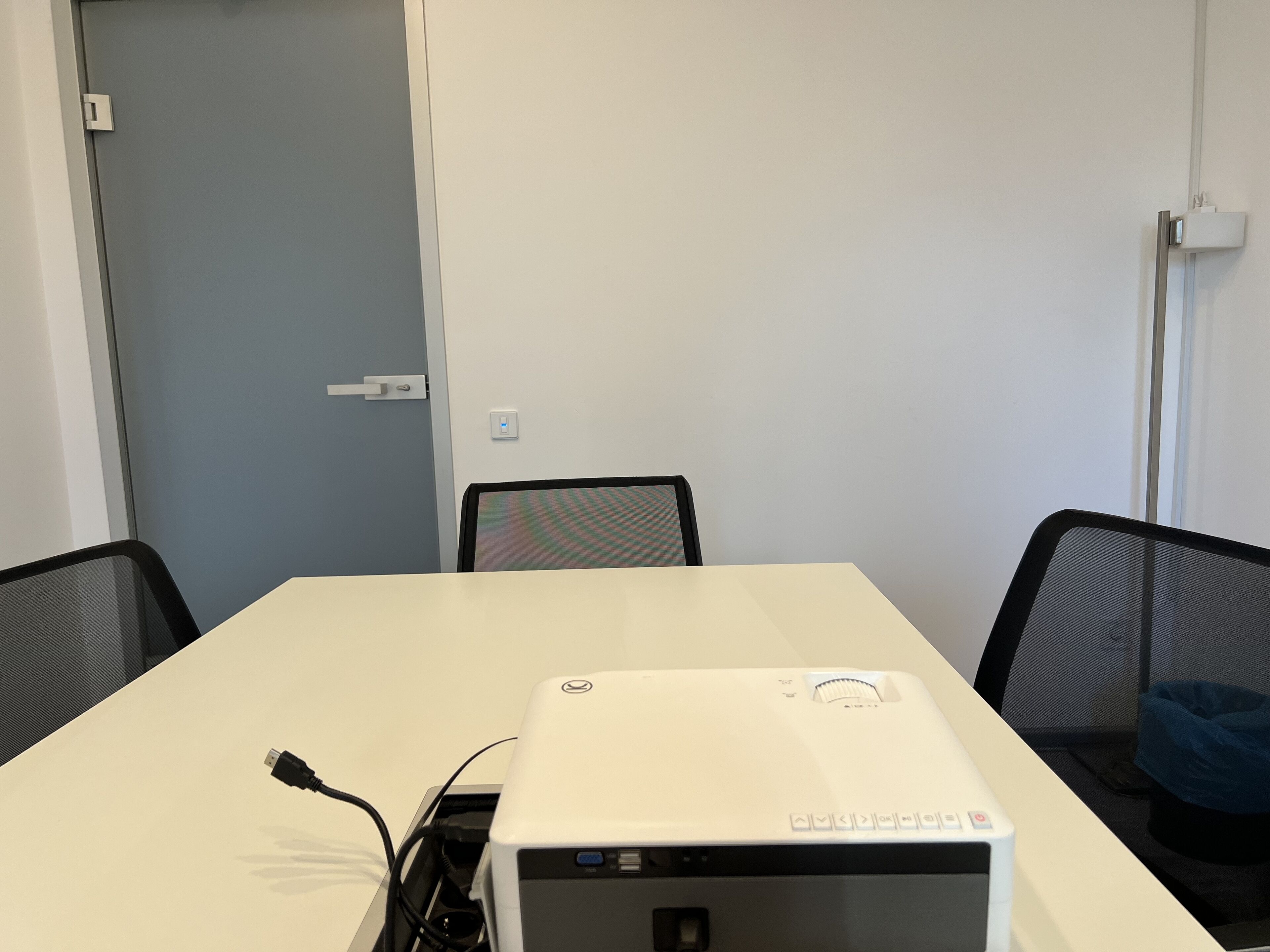 A conference room with a white table, black chairs, and a projector on the table.