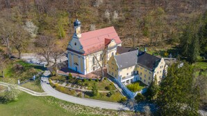 An aerial view of a large, historic building with a prominent tower and a red roof, surrounded by a well-maintained garden and a winding road. - Tools Hotel Laichingen/Ulm (Laichingen)