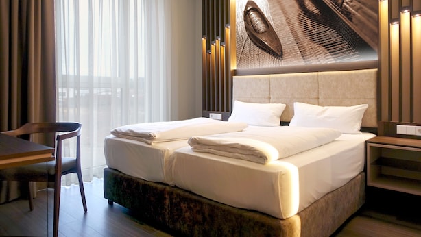 A hotel room with a large bed, a desk, and a chair. - Tools Hotel Laichingen/Ulm (Laichingen)