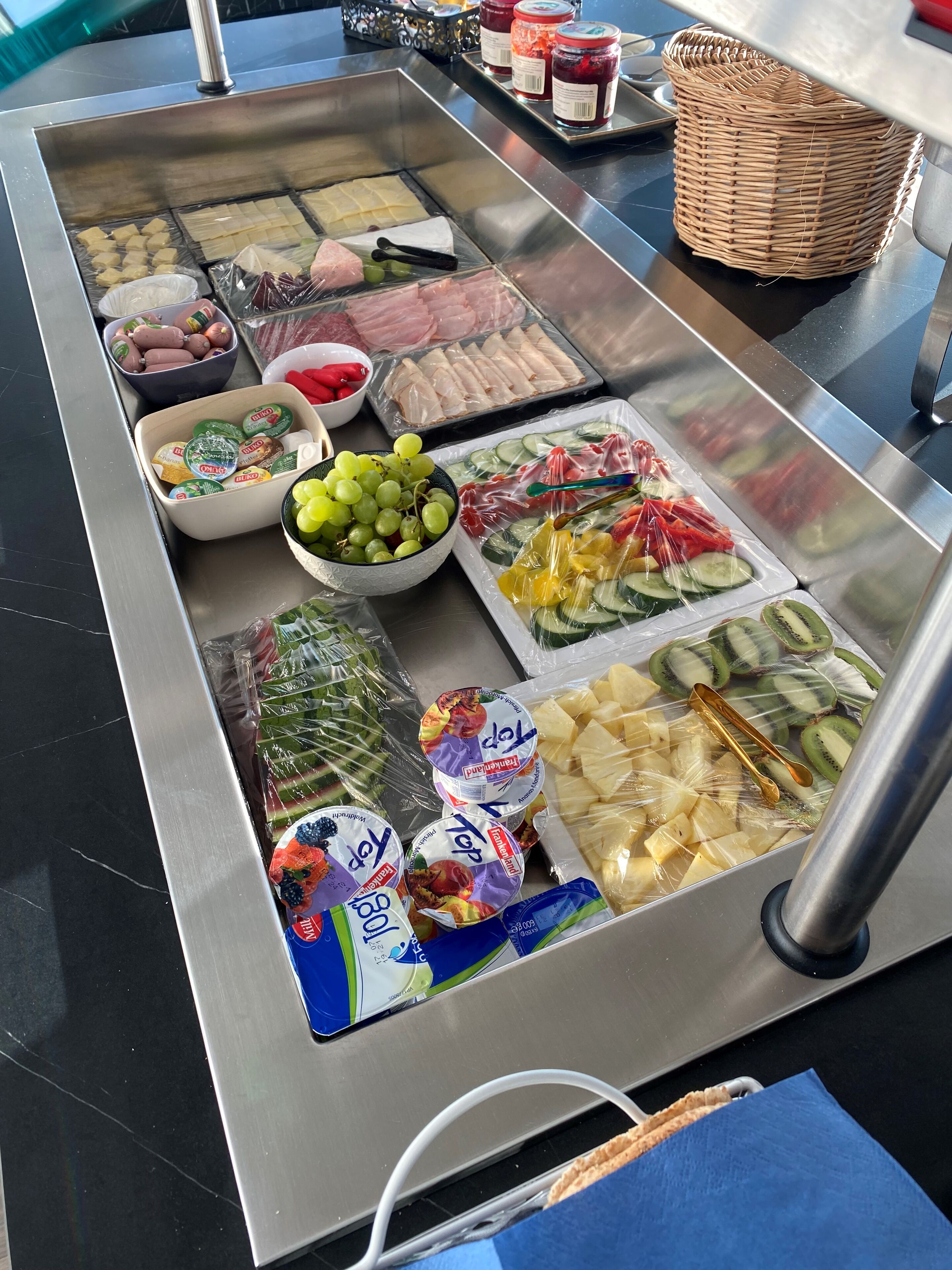 A variety of food items displayed on a stainless steel counter, including fruits, vegetables, and packaged goods.