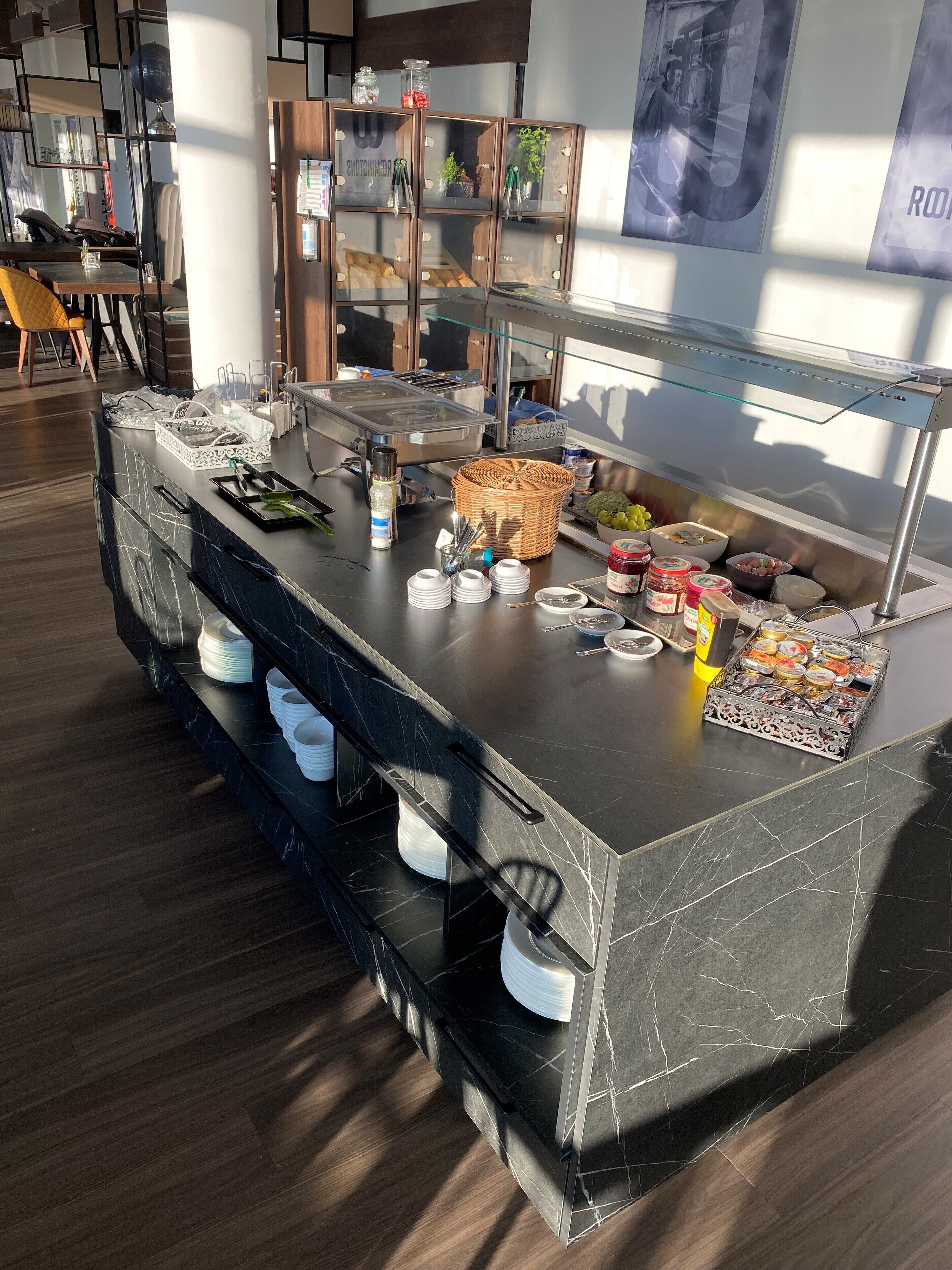 A buffet setup with various food items, a glass display case, and a seating area with chairs and tables.