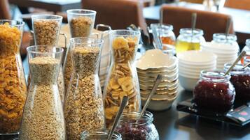 A buffet table with various food items including cereals, fruits, and condiments.