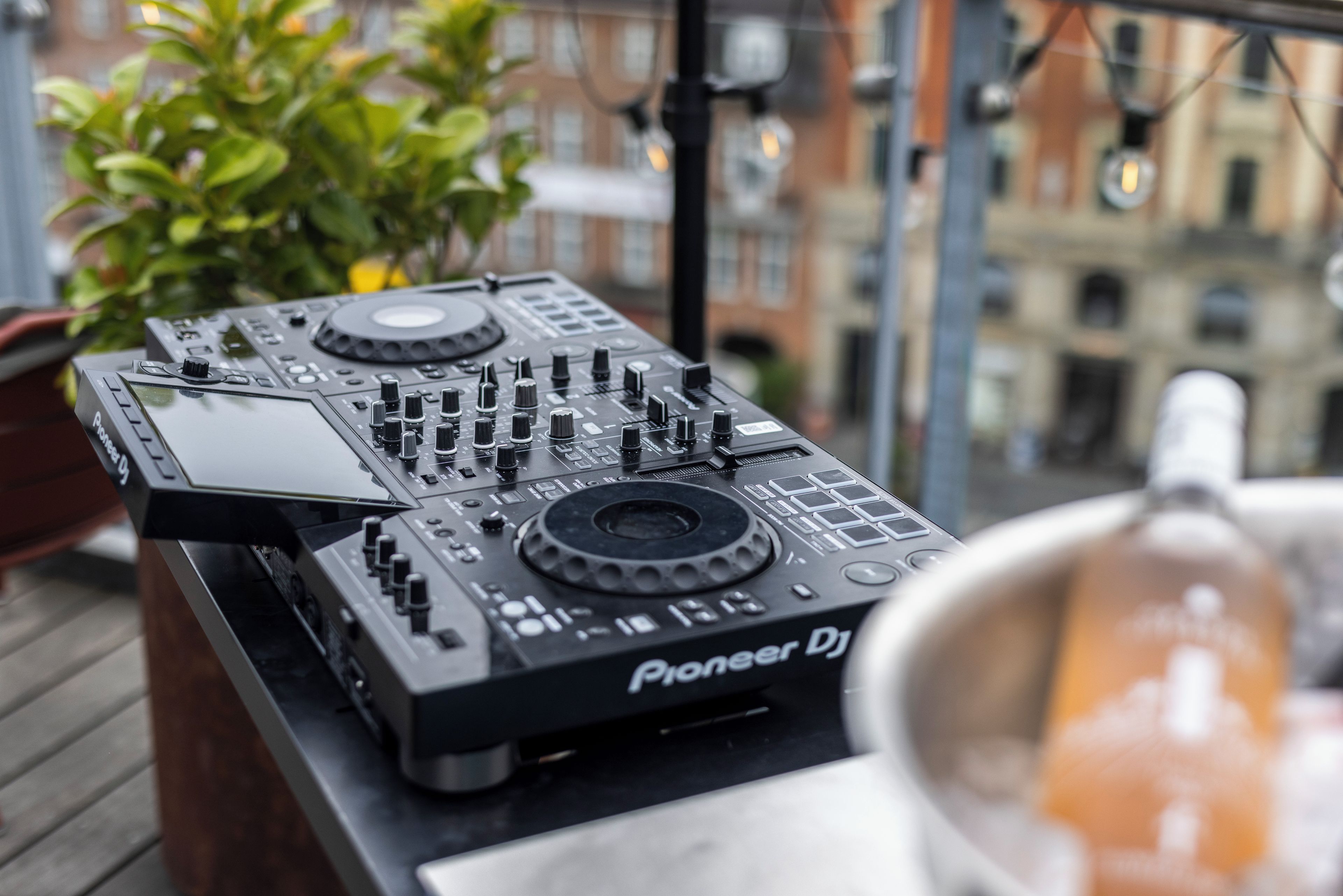Un tocadiscos Pioneer DJ en un balcón con vista a la ciudad al fondo.