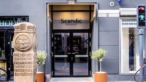 La entrada del hotel Scandic Nørreport, con un pilar de piedra y dos plantas en macetas.