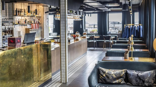Un área de bar moderna con mostrador, asientos y vistas a la ciudad.