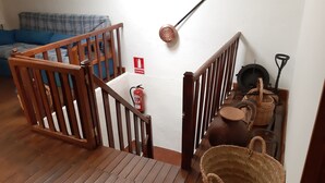 Un escalier en bois, avec un extincteur et une trousse de premiers secours fixés au mur.