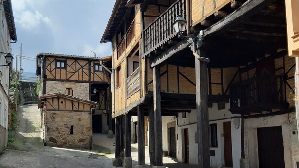 Une rue étroite bordée de bâtiments traditionnels à colombages, de murs en pierre et d’un chemin pavé.