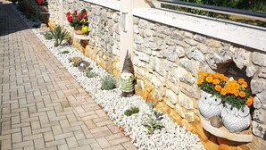 A stone pathway with white pebbles, a metal railing, and decorative owl-shaped planters with orange flowers. - Little blue fish, cute studio for 2 with pool, pets are welcome (Funtana)
