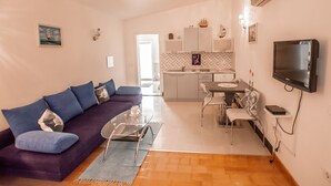 A modern living room with a purple sofa, a glass coffee table, and a dining area with a small table and chairs. - Little blue fish, cute studio for 2 with pool, pets are welcome (Funtana)