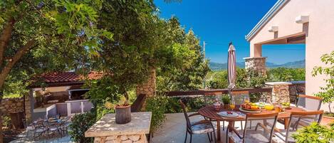 Un patio con mesa y sillas, rodeado de muros de piedra y follaje.