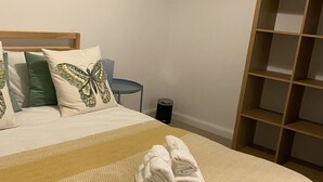 A neatly made bed with a patterned bedspread, two rolled towels, and pillows with a butterfly design. - Serenity by the Canal House near City Centre with 2 Parking ( Sleeps 5 ) (Coventry)