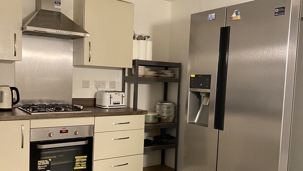 A compact kitchen with a stainless steel refrigerator, a built-in oven, and a gas stove. - Serenity by the Canal House near City Centre with 2 Parking ( Sleeps 5 ) (Coventry)