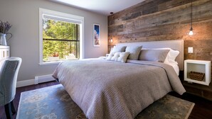 A bedroom with a large bed, a desk, and a window with a view of trees. - 101McCloud 2BR/2BA Incline Village | Hot Tub (Incline Village)