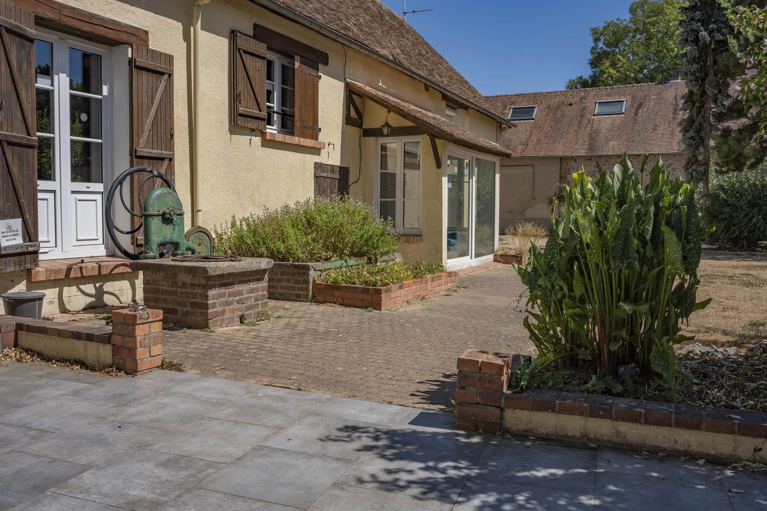 Il s’agit d’un bâtiment traditionnel doté d’une cour intérieure, où l’on trouve une pompe à eau, des jardinières en briques et un grand cactus.