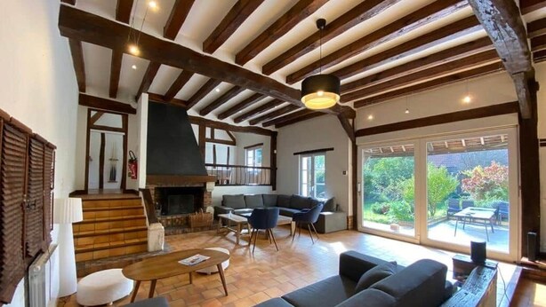 Un salón amplio con chimenea, muebles modernos y vistas al exterior.