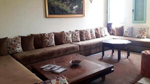 A living room with a brown sofa, a coffee table, and a painting on the wall. - Residence Atlas Hivernage 4841 (Marrakech)