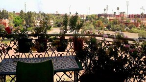 A balcony with a table and chairs, surrounded by potted plants and flowers. - Residence Atlas Hivernage 4841 (Marrakech)
