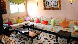 Ein Wohnzimmer mit einem blumigen Sofa, zwei Couchtischen und einem gemusterten Teppich.