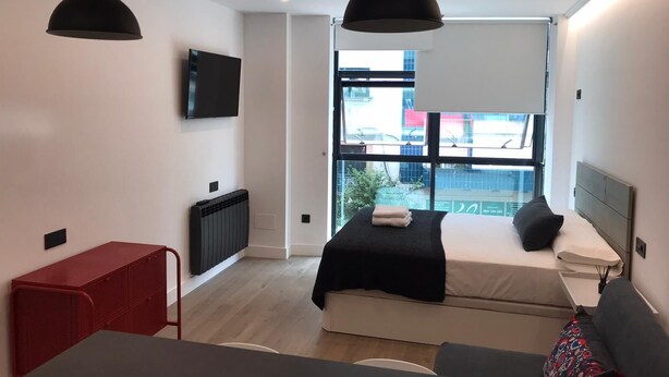 Quarto moderno com cama, escrivaninha e um móvel de armazenamento vermelho.