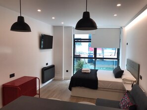 Un dormitorio moderno con una cama, un escritorio y un módulo de almacenamiento rojo.