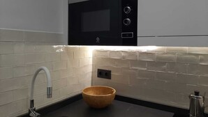 Uma cozinha moderna com micro-ondas embutido, uma tigela de madeira no balcão e uma cafeteira.