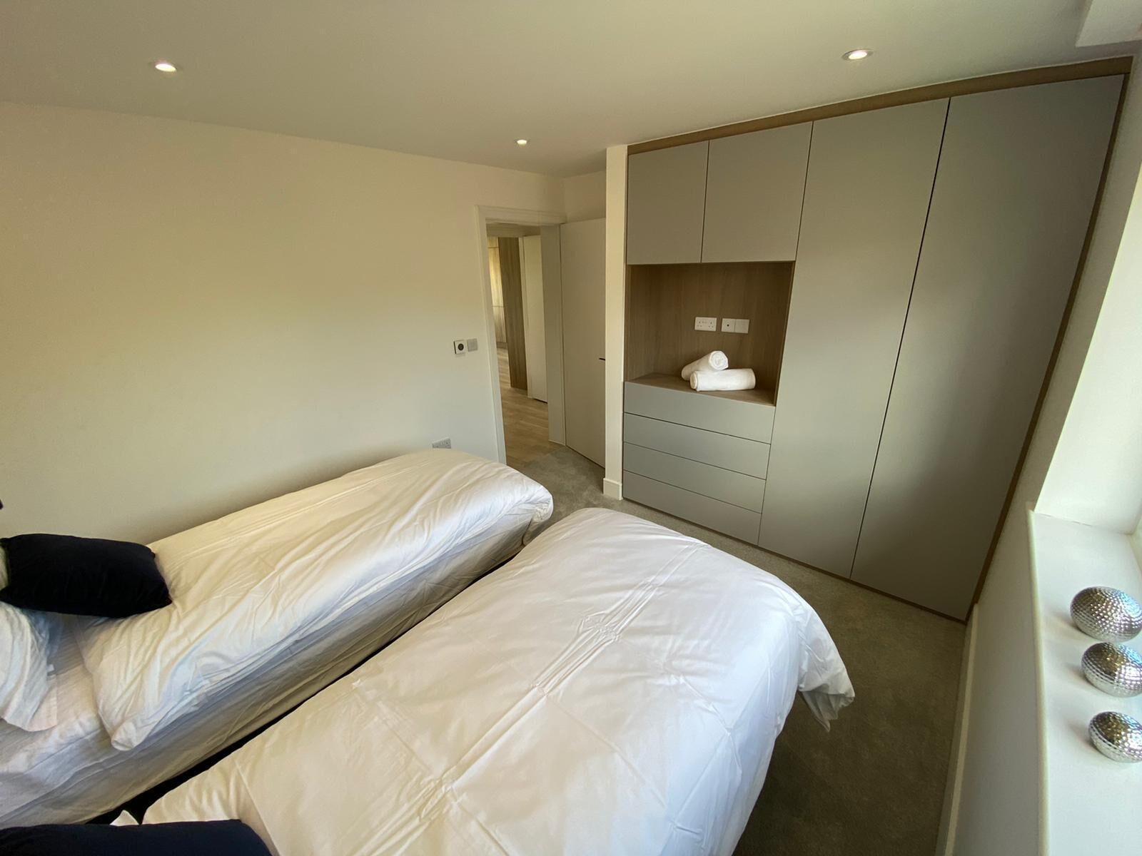 A hotel room with two single beds, a wardrobe, and a small seating area.