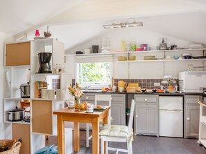 Une cuisine avec des meubles blancs, une table en bois et une fenêtre.
