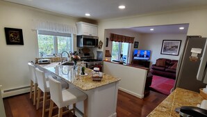 A modern kitchen with a central island, bar stools, a microwave, and a stove.