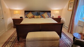 Ein Schlafzimmer mit einem großen Bett, zwei Nachttischen, einem Beistelltisch, einem Sessel und einem kleinen Tisch.