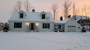 A two-story house with a red door, multiple windows, and a garage.