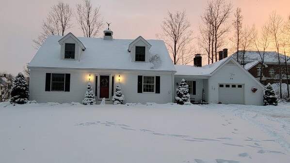 A two-story house with a red door, multiple windows, and a garage.
