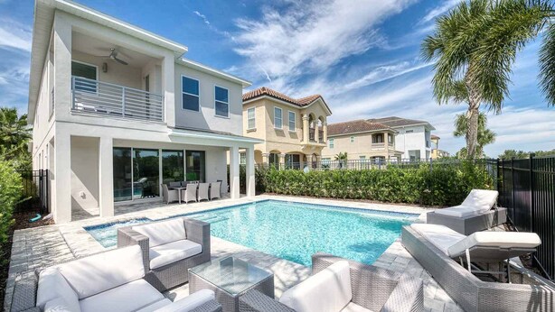 Une maison moderne dotée d’une piscine, de mobilier d’extérieur et d’un jardin bien entretenu.