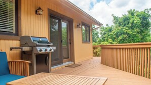 Una terraza de madera con una parrilla, una mesa y una silla azul.