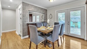 A dining area with a wooden table, six chairs, and a view of the backyard through a glass door. - Hot Tub | Sauna | Fire Pit | Outdoor Living | Elegant Ranch (Ann Arbor)