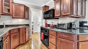 A kitchen with wooden cabinets, a microwave, a toaster, and a coffee maker. - Hot Tub | Sauna | Fire Pit | Outdoor Living | Elegant Ranch (Ann Arbor)