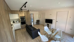 A modern apartment with a kitchen, dining area, living room, and a TV. - Brand New 2 Bedroom Flat (Reading)