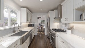 Una cocina moderna con armarios blancos, electrodomésticos de acero inoxidable y suelo de madera.
