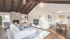 Un salón amplio con chimenea, televisor y comedor con mobiliario de madera.