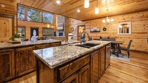 A spacious kitchen with wooden walls, granite countertops, and a large island.