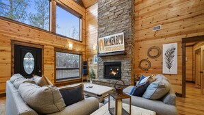 A cabin with a stone fireplace, wooden walls, and a sign reading "Broken Bow Cabin Lodging."
