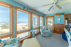 Ein Zimmer mit großen Fenstern, einem Deckenventilator und Blick auf den Strand.