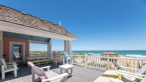 A wooden deck with Adirondack chairs, a small table, and a gazebo overlooking the ocean. - Beach Royalty - Nags Head MP 15.5, Luxury Oceanfront, Private Walk to Beach, Elevator, Pool, Hot Tub (Nags Head)