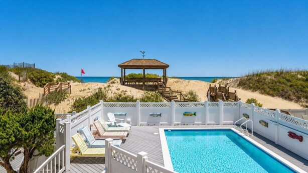 A beachside pool area with lounge chairs, a gazebo, and a view of the beach. - Beach Royalty - Nags Head MP 15.5, Luxury Oceanfront, Private Walk to Beach, Elevator, Pool, Hot Tub (Nags Head)