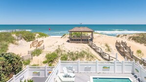 A beach view with a gazebo, wooden deck, lounge chairs, and a pool. - Beach Royalty - Nags Head MP 15.5, Luxury Oceanfront, Private Walk to Beach, Elevator, Pool, Hot Tub (Nags Head)