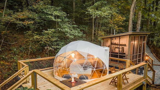 A geodesic dome structure with a fire pit, wooden deck, and a small wooden building with a glass door. - Hot Tub, Views, Outdoor Oasis (Todd)