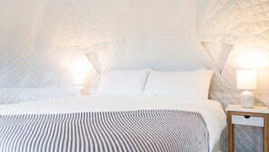 A bedroom with a quilted headboard, a bed with white bedding, two bedside tables with lamps, and a striped throw blanket. - Hot Tub, Views, Outdoor Oasis (Todd)